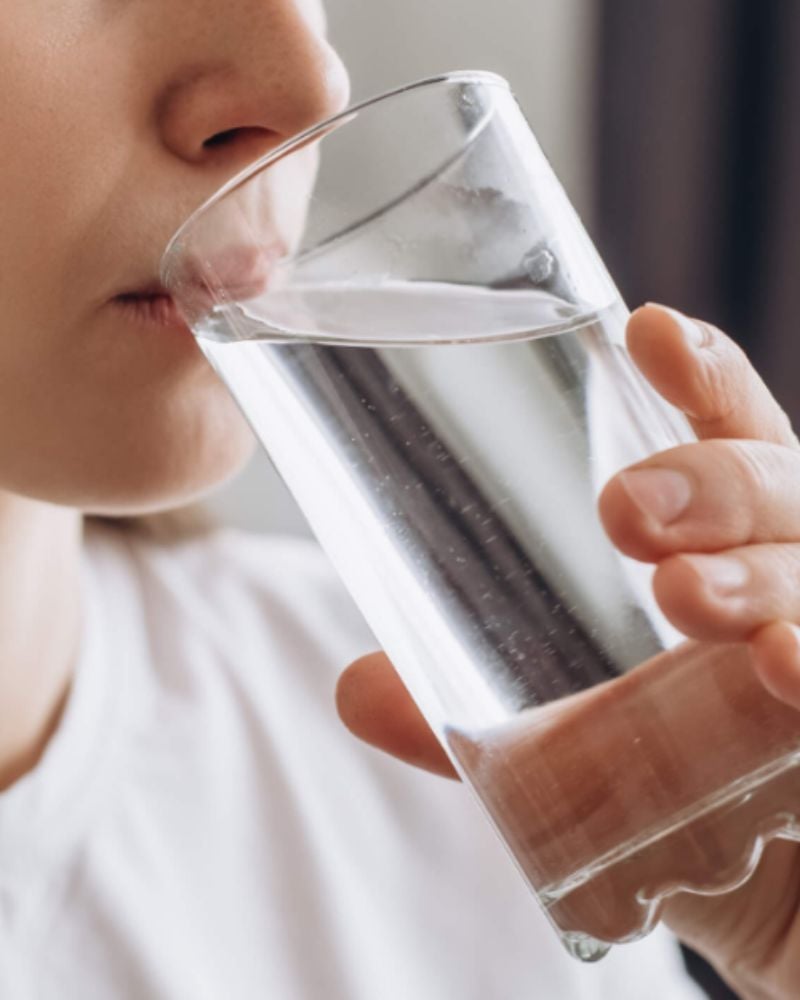 Persona che beve acqua da una bottiglia