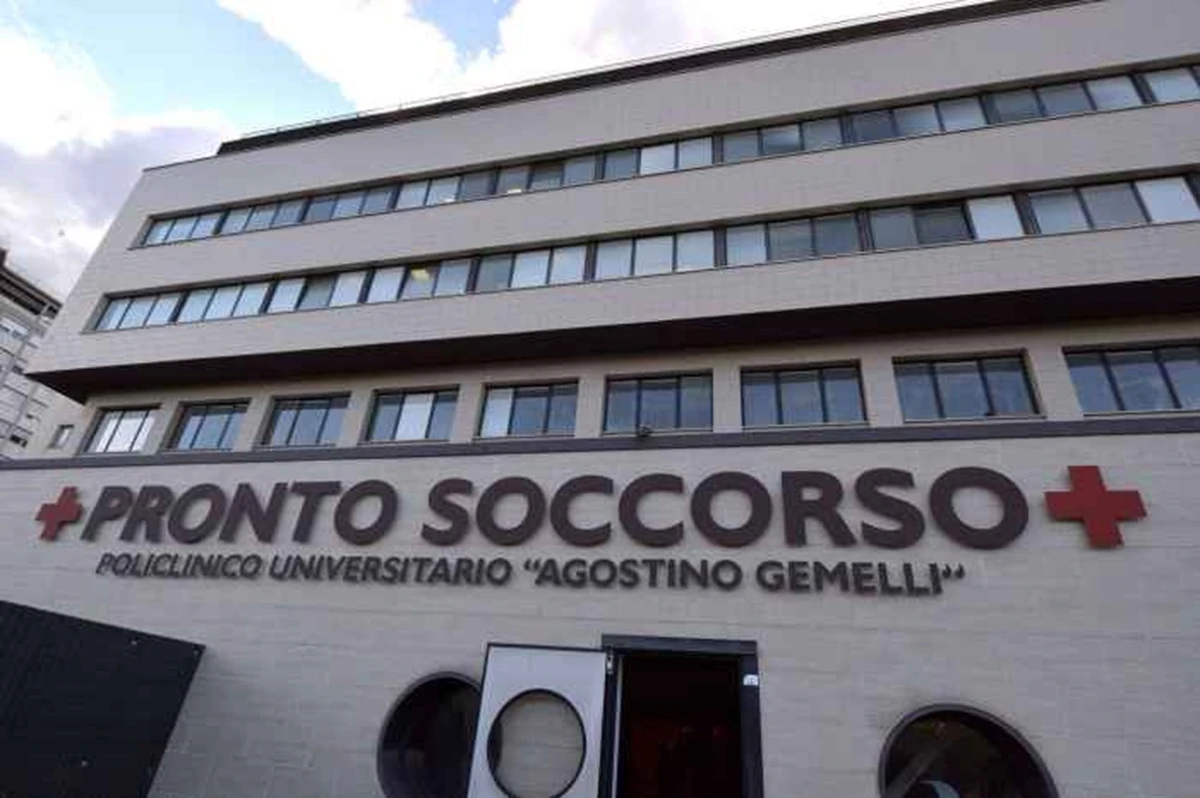 Ingresso dell'ospedale Gemelli di notte, luci accese e atmosfera tesa